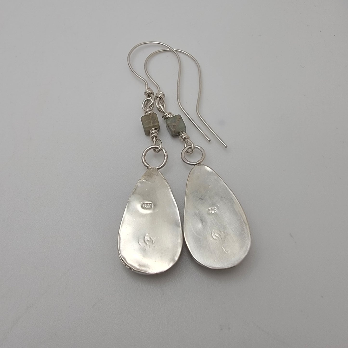 Back view of sterling silver teardrop shaped dangle earrings against white background