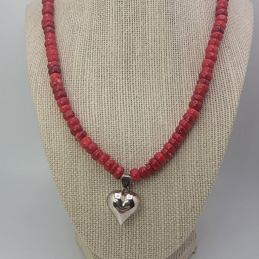 Red beaded neckalce with silver heart on beige necklace display against white background
