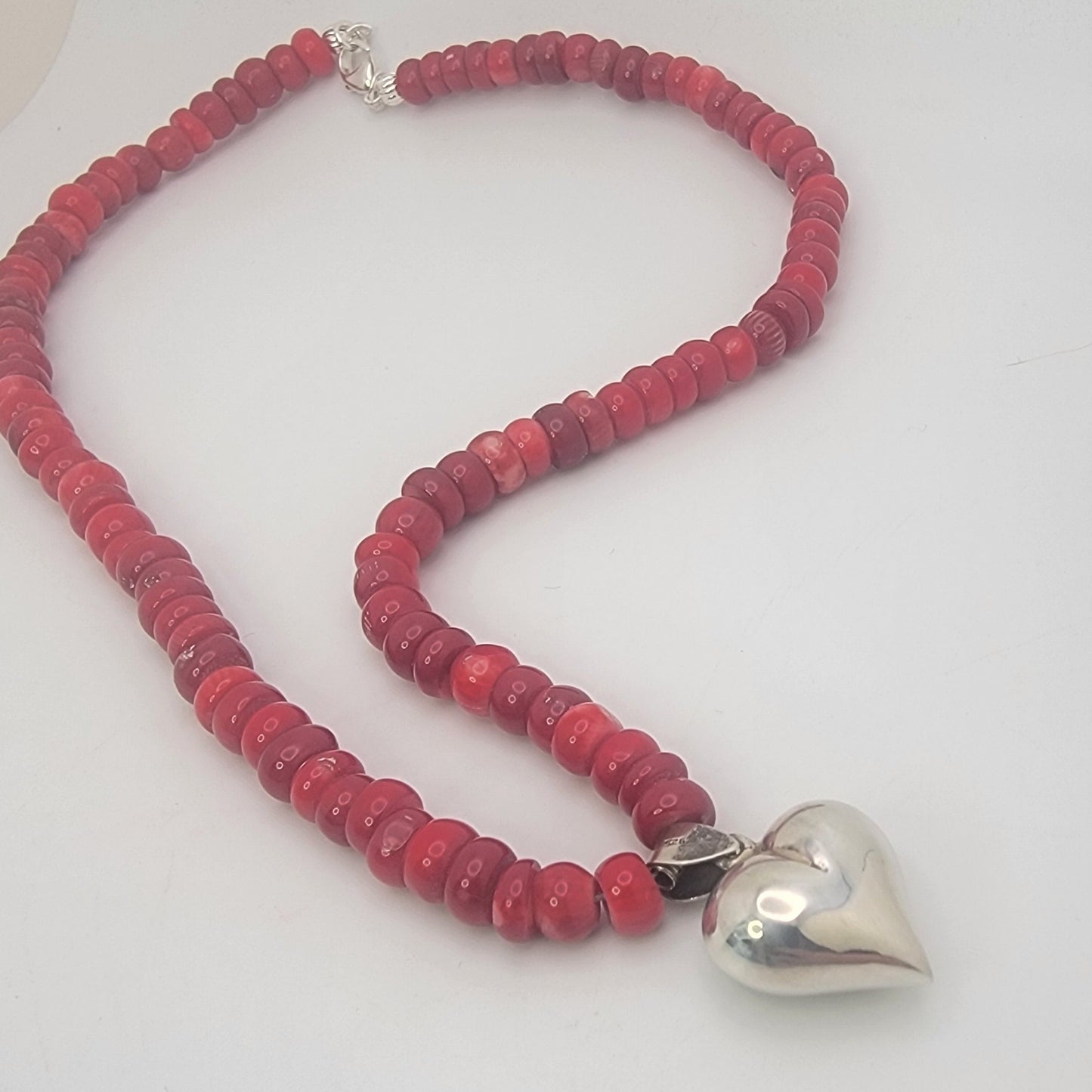 Red beaded neckalce with silver heart on white background