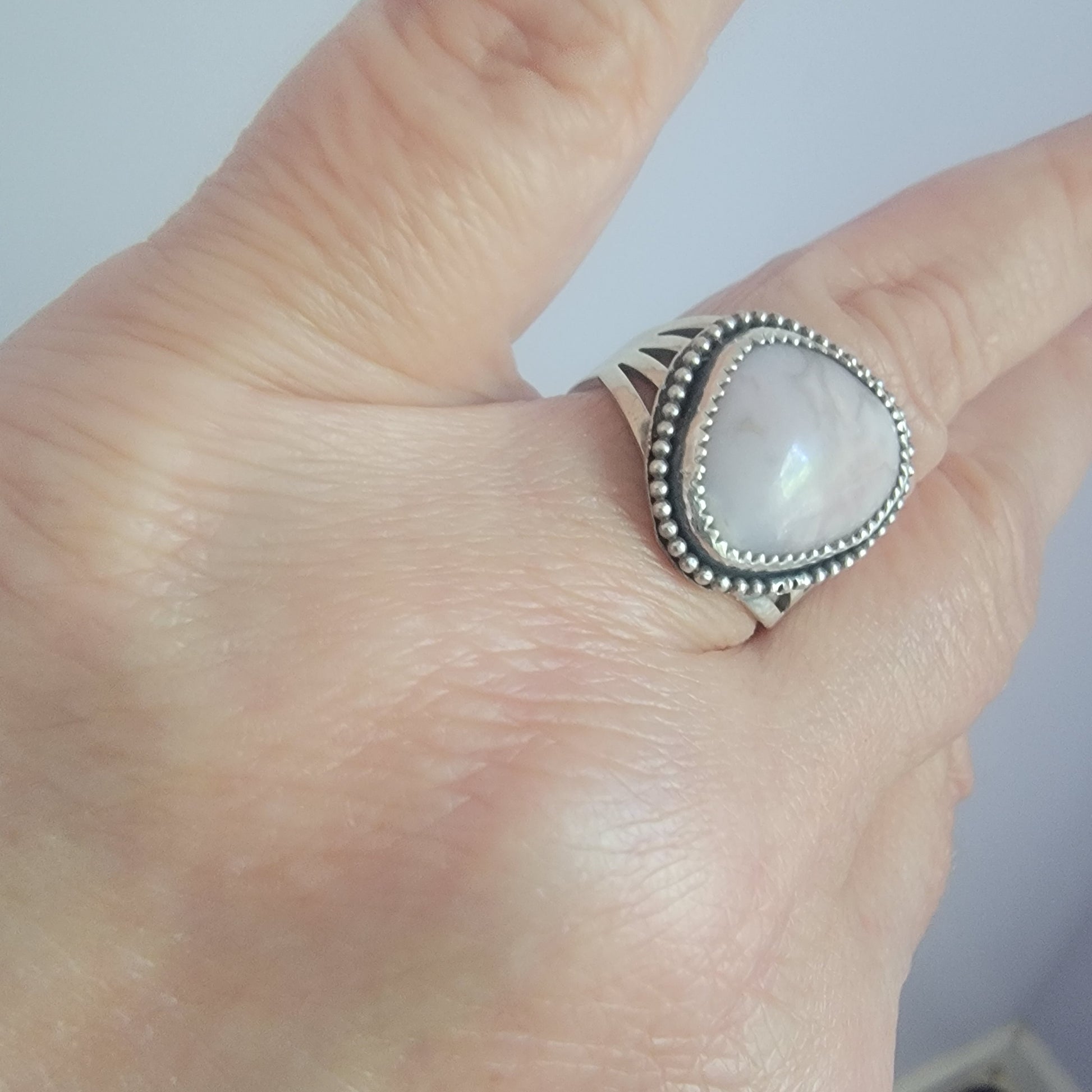 Pink gemstone and sterling silver ring with oxidized beaded detail shown on hand