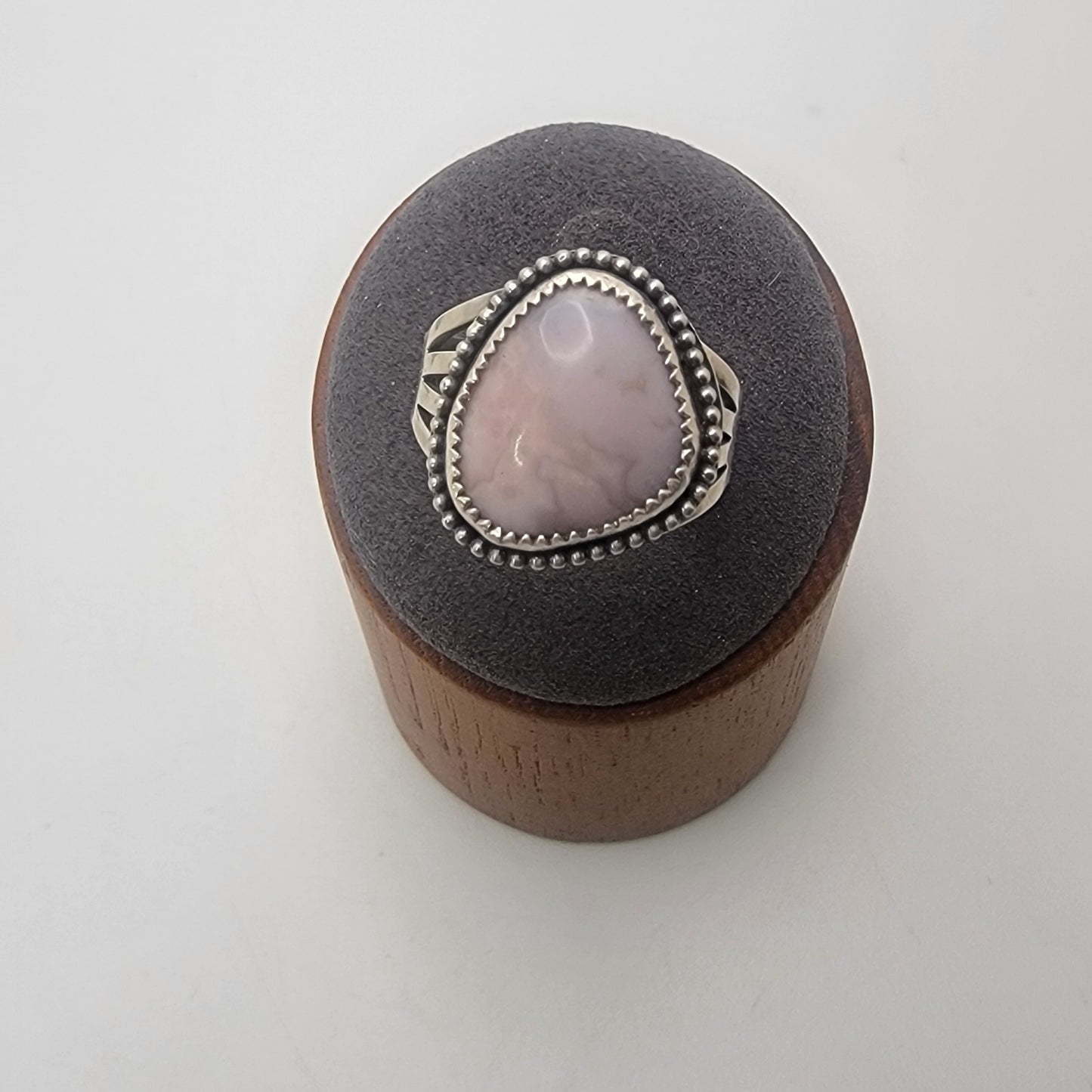 Pink gemstone and sterling silver ring with oxidized beaded detail shown on gray ring stand