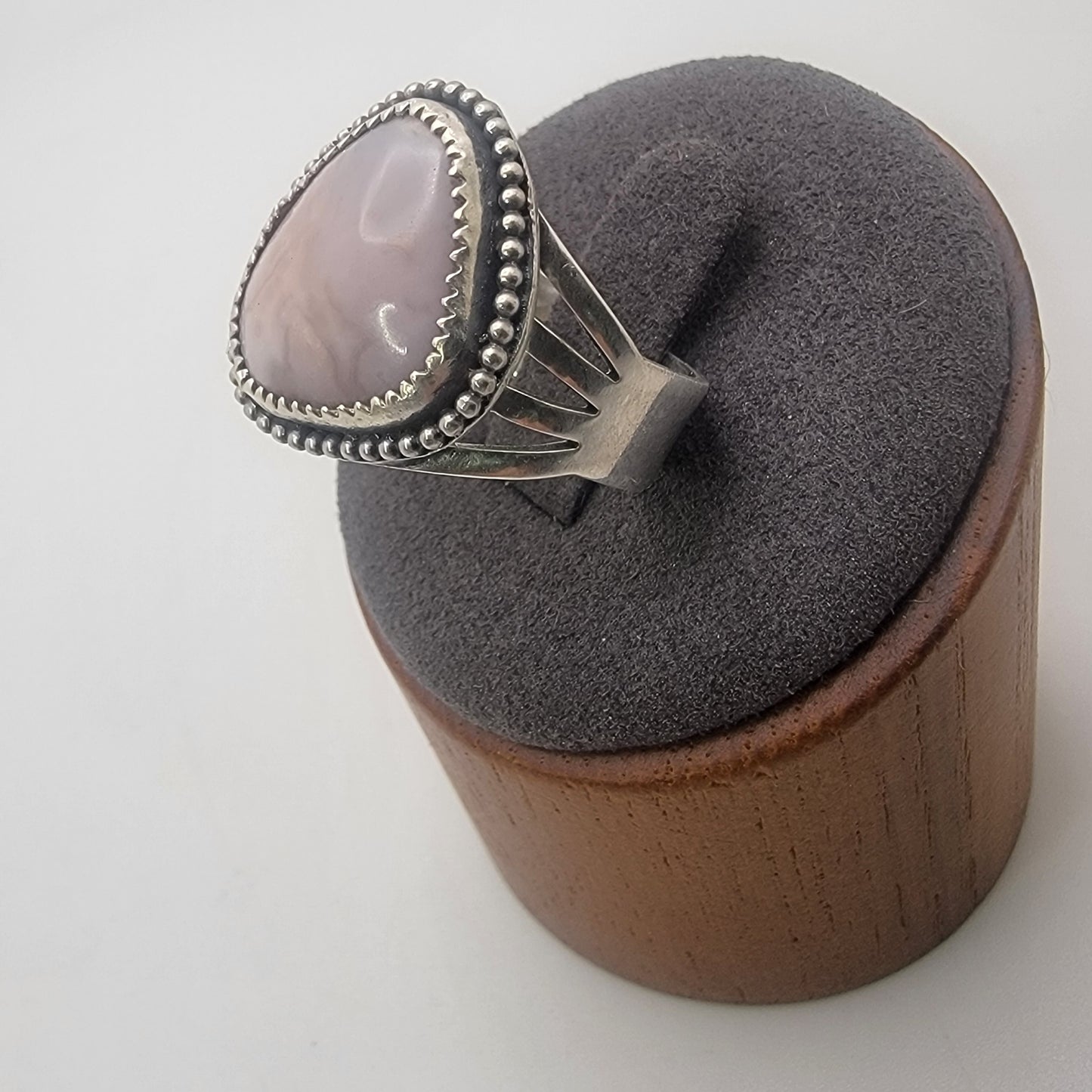 Pink gemstone and sterling silver ring with oxidized beaded detail shown on gray ring stand