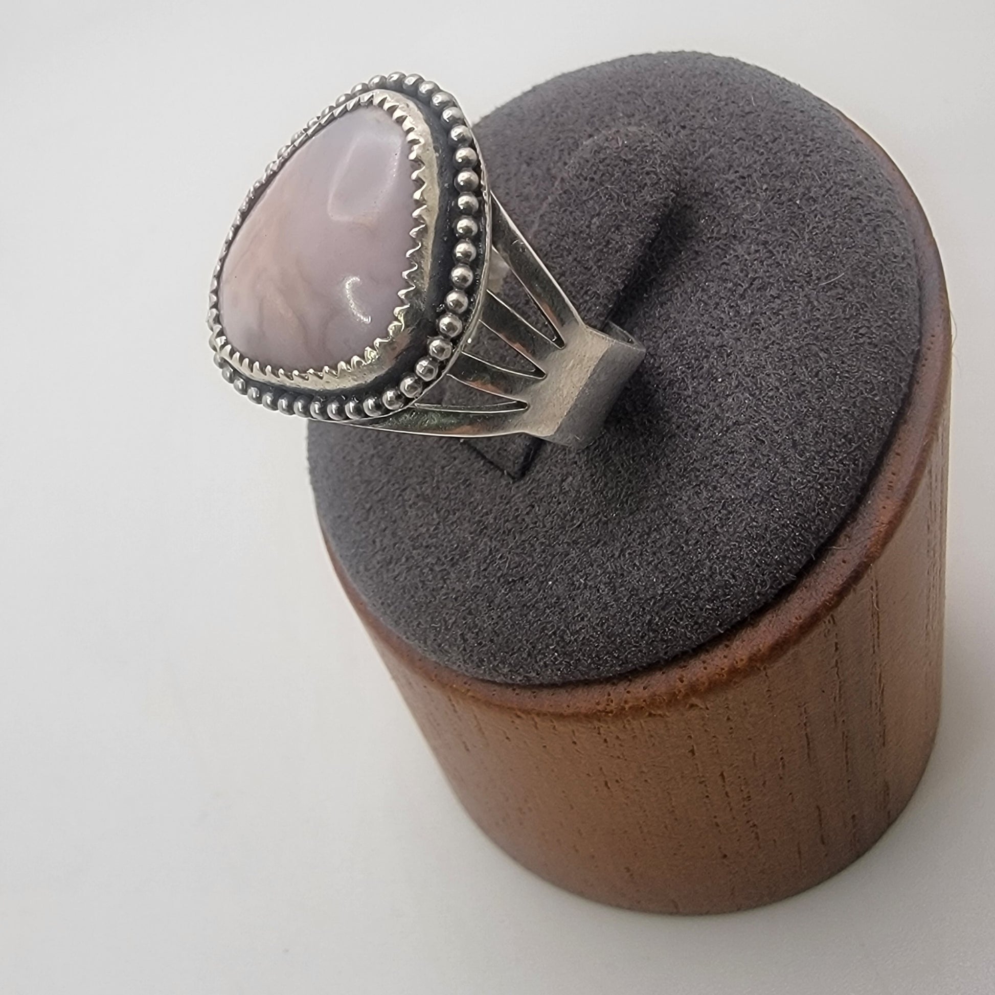 Pink gemstone and sterling silver ring with oxidized beaded detail shown on gray ring stand