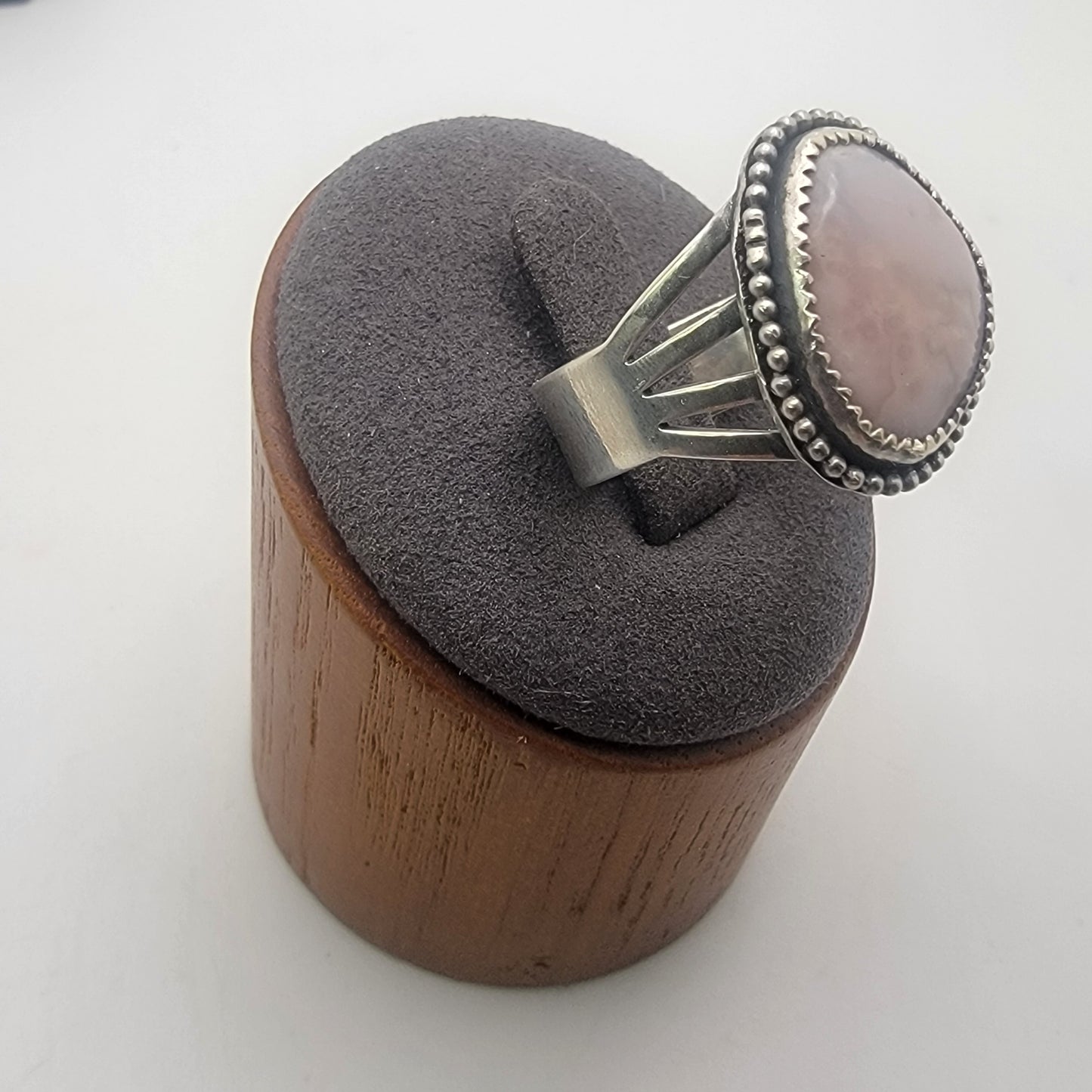 Pink gemstone and sterling silver ring with oxidized beaded detail shown on gray ring stand