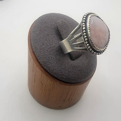 Pink gemstone and sterling silver ring with oxidized beaded detail shown on gray ring stand