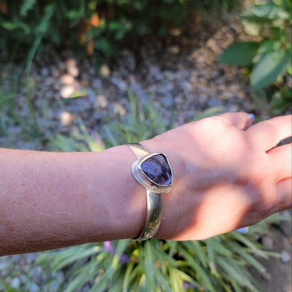 Triangle shaped purple agate cabochon bangle bracelet worn on wrist in natural environment