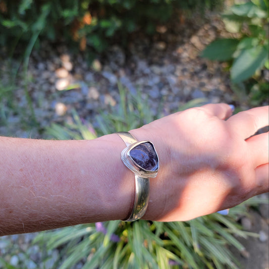 Triangle shaped purple agate cabochon bangle bracelet worn on wrist in natural environment