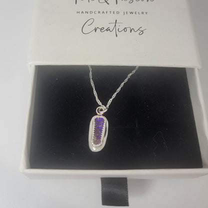 A silver pendant necklace with a purple textured inlay, displayed inside an open white jewelry box with a black velvet insert. The inside lid of the box is printed with the brand name 'Tinsley & Tinsley Creations'.