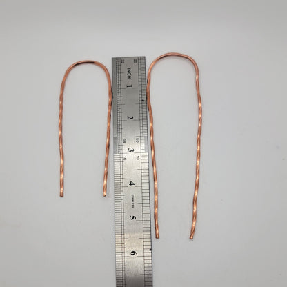 2 hair pins next to a metal ruler on a white background