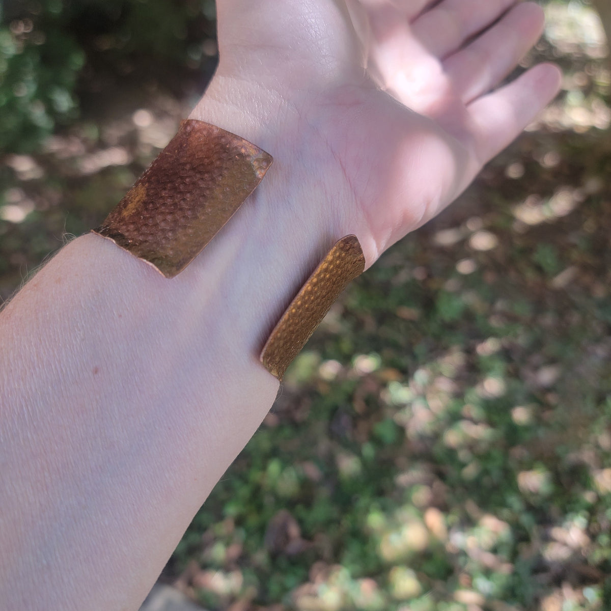 Underside of copper cuff on a wrist showing the opening.