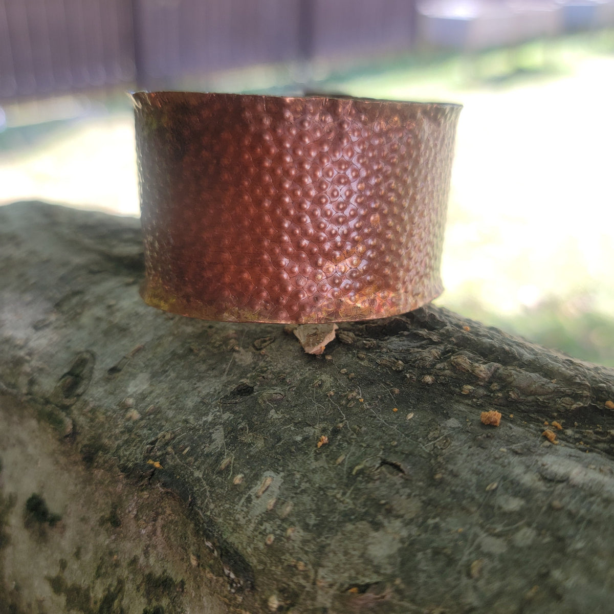 Front view of wide copper cuff resting outdoors.