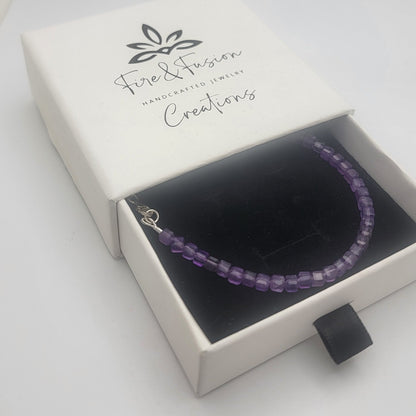 A purple beaded bracelet displayed inside an open white jewelry gift box with a black interior. The box lid is printed with the brand name 'Fine & Fierce Creators'.