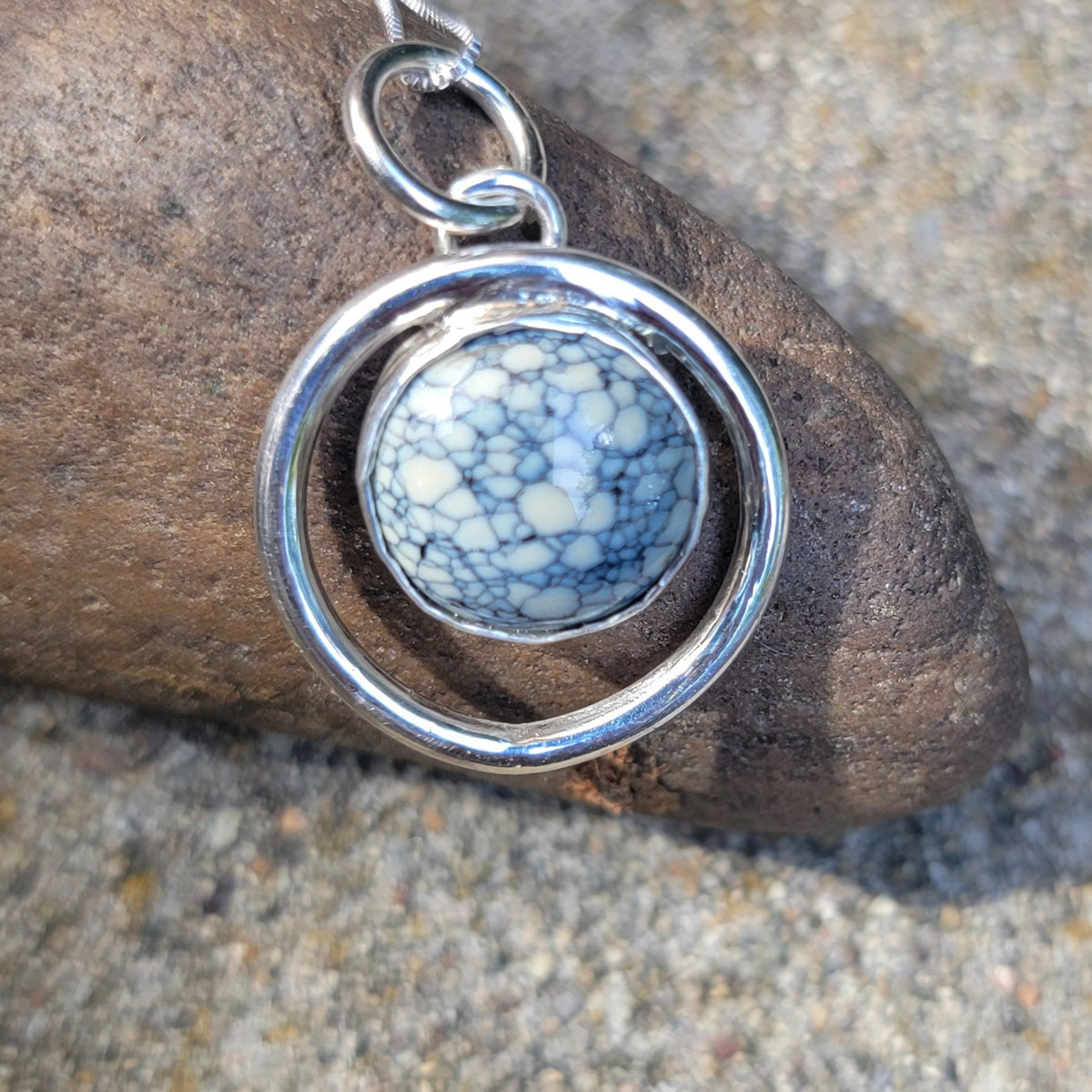 Handmade variscite pendant within an open sterling silver circle with a brown stone as a background
