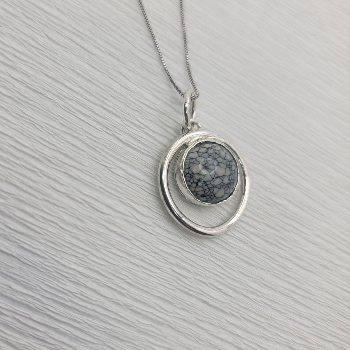 Variscite circle pendant and sterling silver box chain on a light textured background.