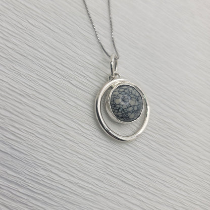 Variscite circle pendant and sterling silver box chain on a light textured background.