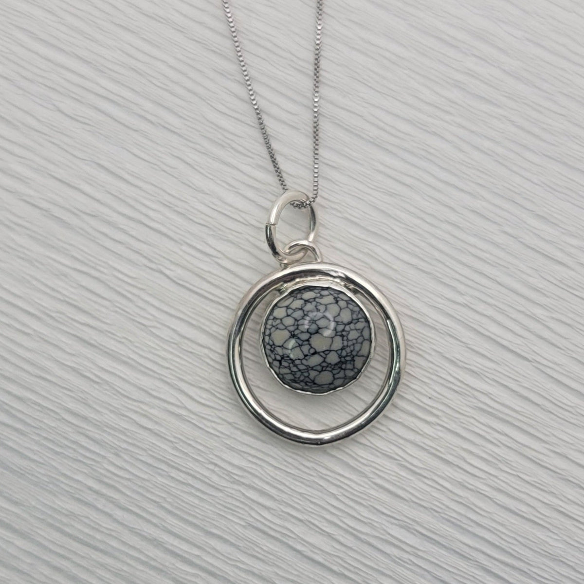 Variscite circle pendant and sterling silver box chain on a light textured background.