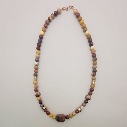 Earth tone beaded necklace with copper and bronze accent beads on a light background