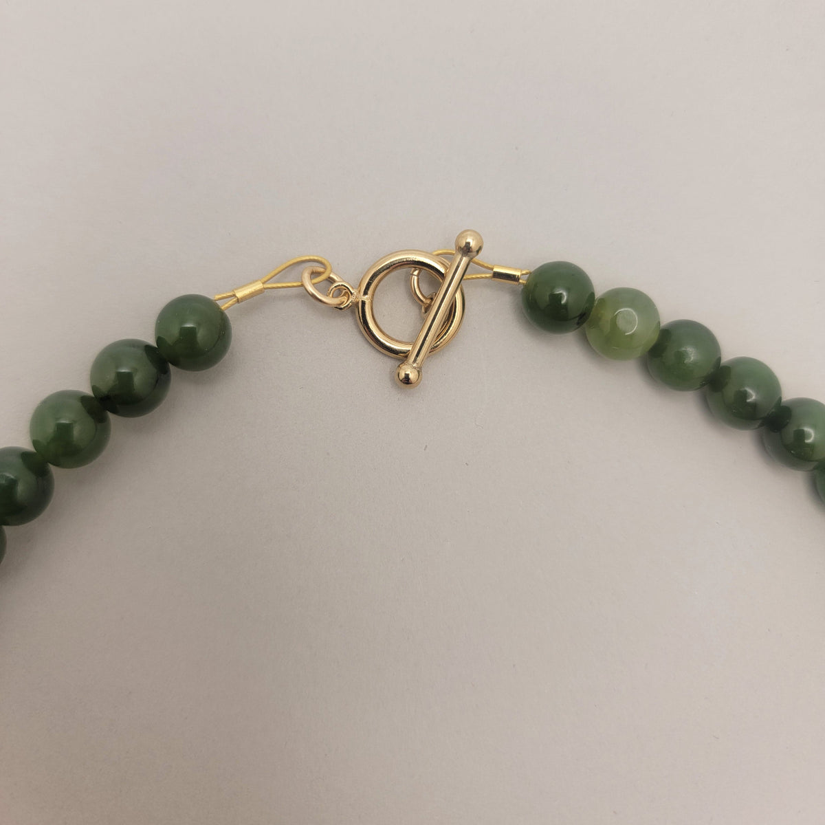 Close view of the gold-filled toggle clasp and polished green jade beads.