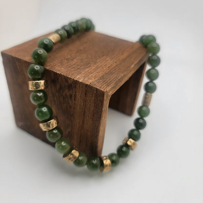 Green jade necklace draped over a wooden display block, showing textured bronze accent beads.
