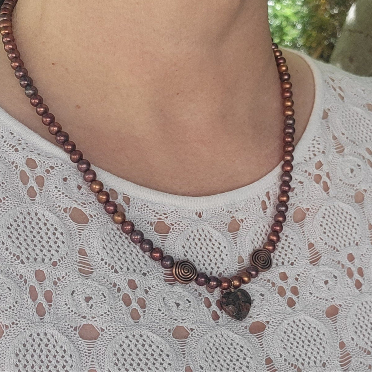 Rust pearl necklace worn with a white eyelet top, showing copper swirl accents and a feldspar heart focal.