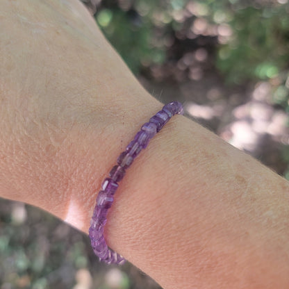 A purple beaded bracelet worn on a wrist in an outdoor environment