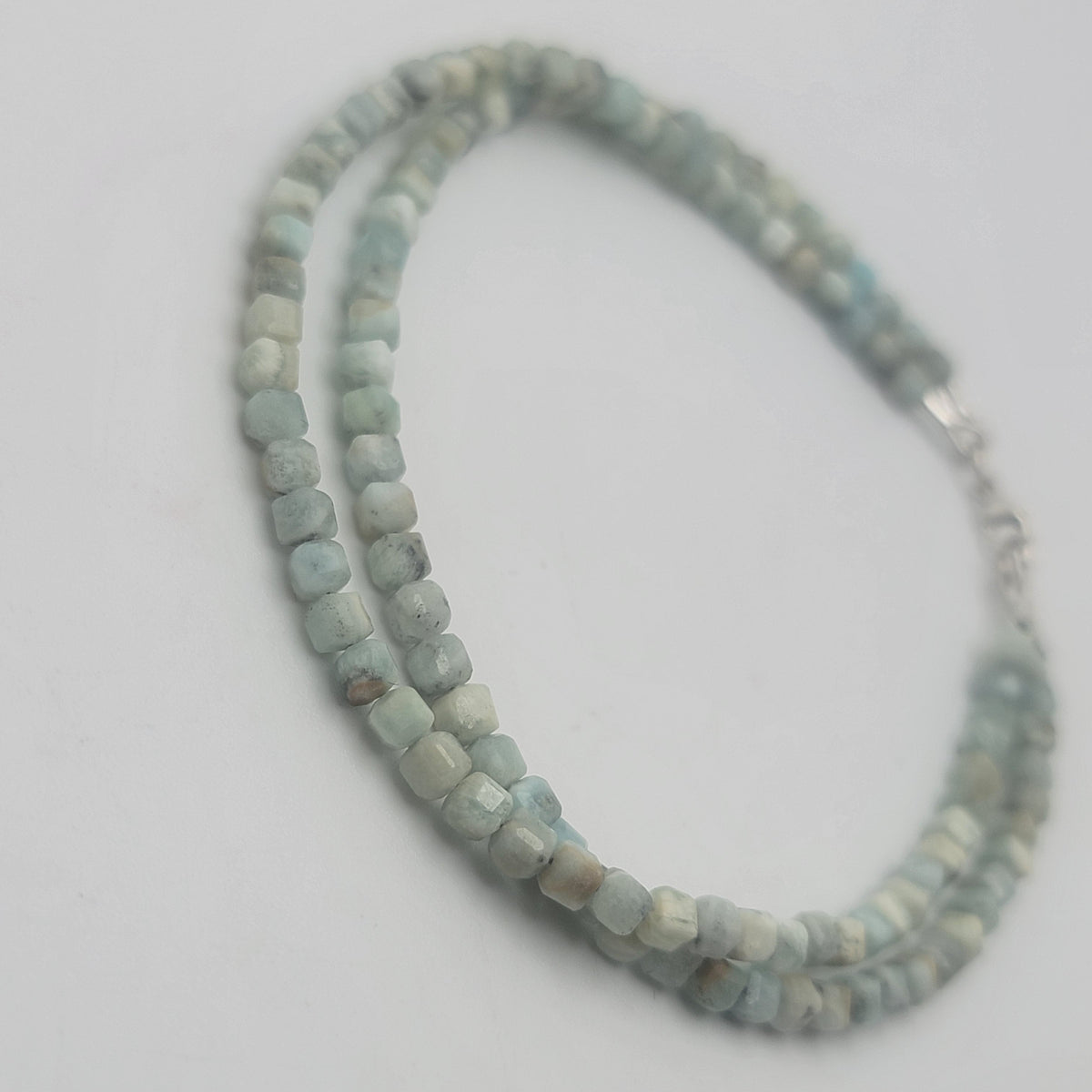 A double-strand beaded bracelet made of light blue-green stone beads with a silver clasp, photographed on a plain light gray background.