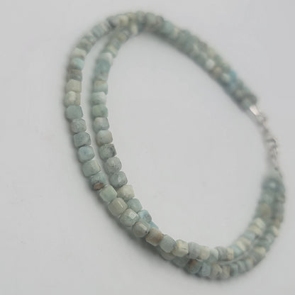 A double-strand beaded bracelet made of light blue-green stone beads with a silver clasp, photographed on a plain light gray background.