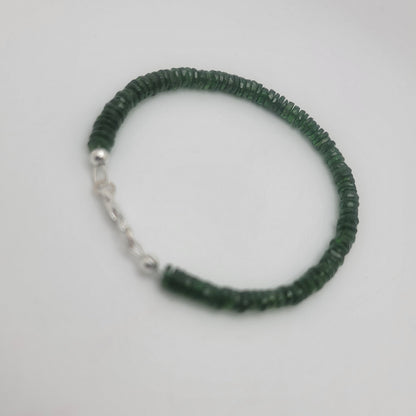 A dark green beaded bracelet with a silver chain extender, photographed on a plain light gray background.