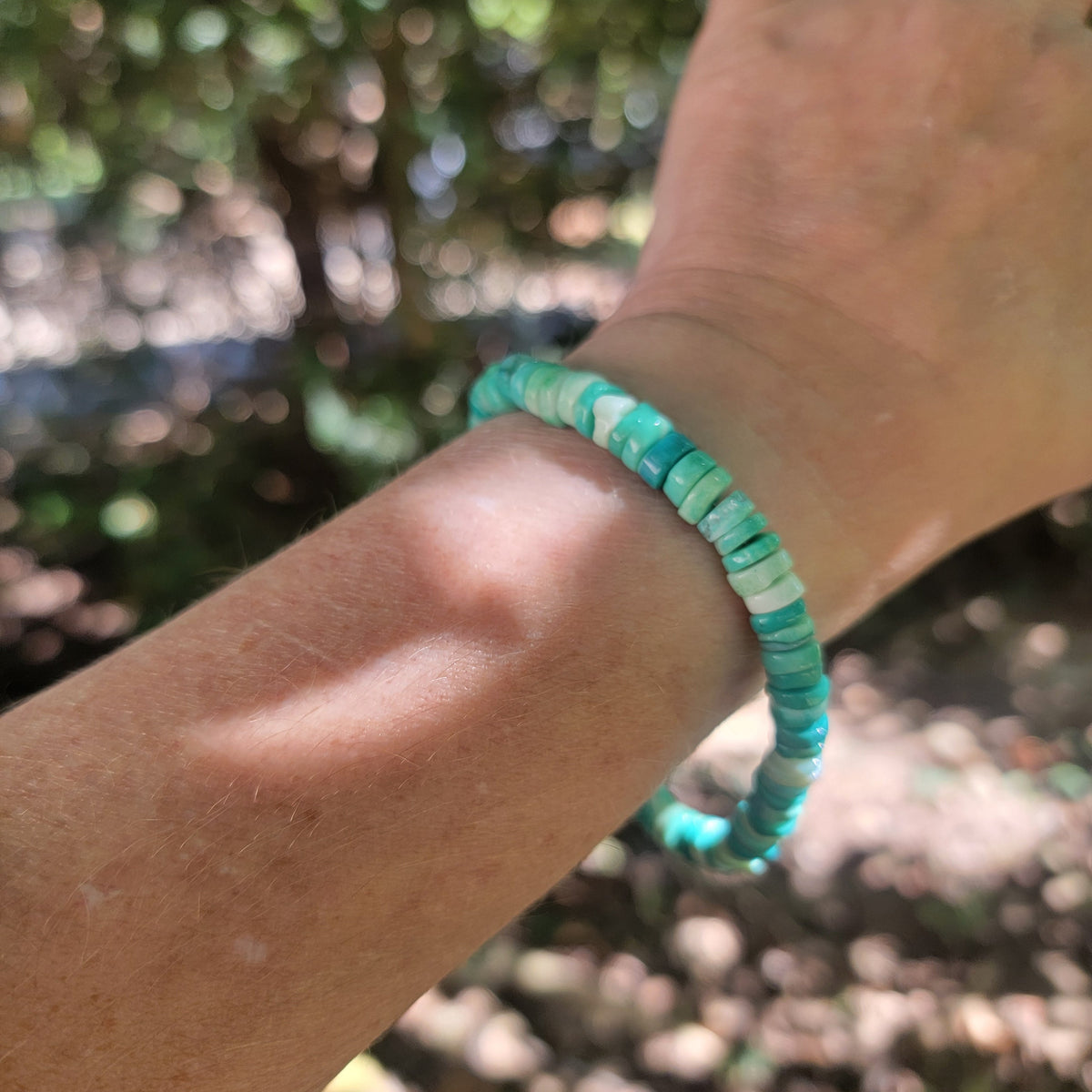 Green Peruvian Opal beaded bracelet worn on a wrist in an outdoor environment.