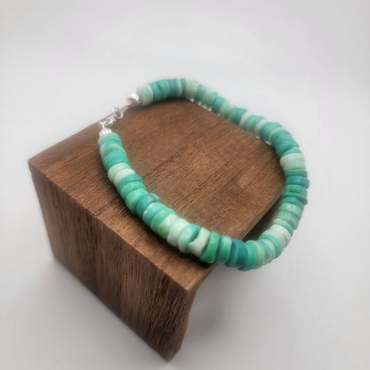 Peruvian opal beaded bracelet finished with a sterling silver lobster clasp on a wood platform on a white background.