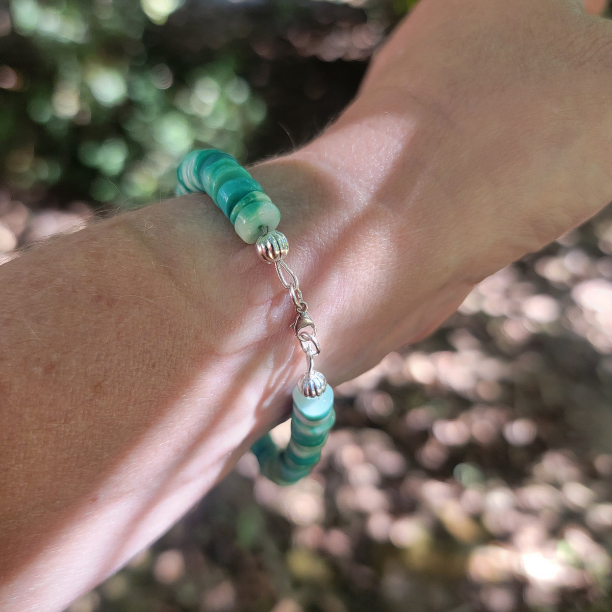 Peruvian opal beaded bracelet finished with a sterling silver lobster clasp worn on a wrist in an outdoor environment.