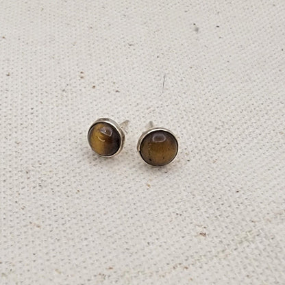 Pair of round stud earrings with brown gemstones on a textured white background