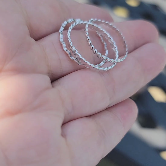 Video of a hand holding 3 silver stacking rings with different designs