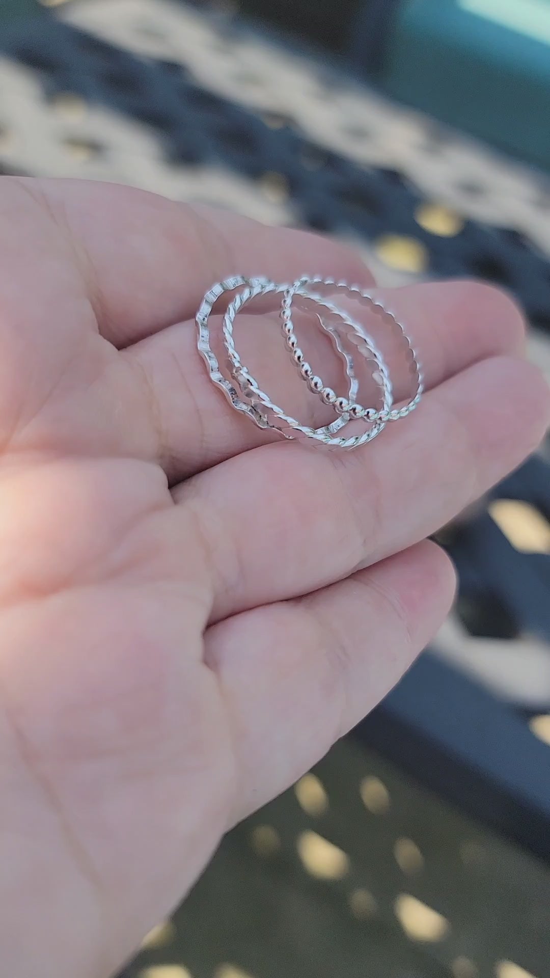 Video of a hand holding 3 silver stacking rings with different designs