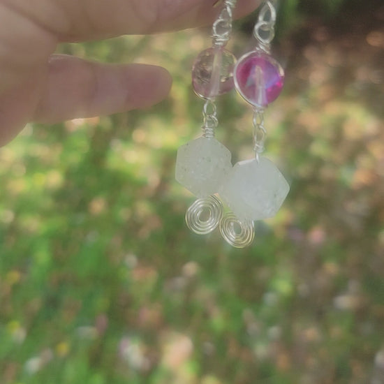 Hand holding a pair of pink and crystal dangle earrings with silver wire wrap and ear wires