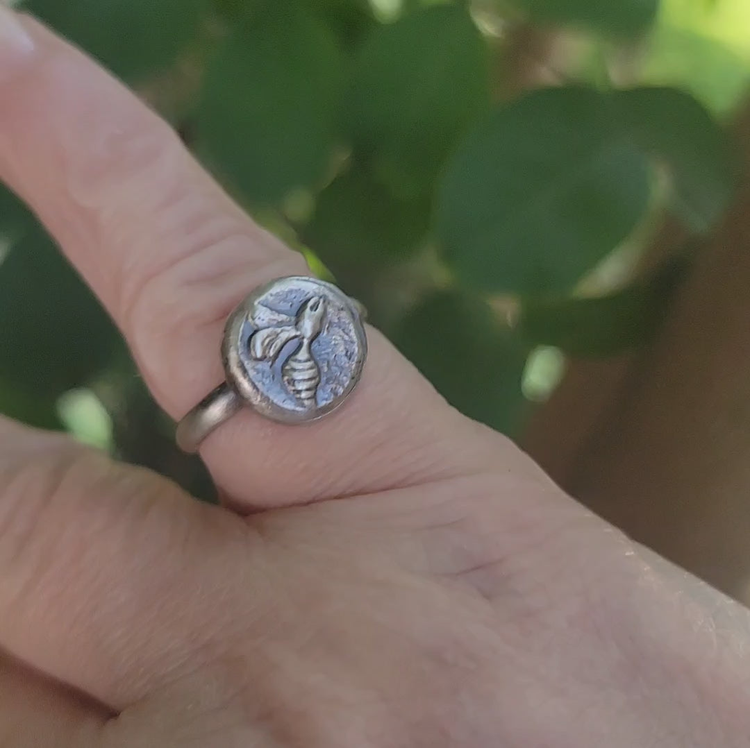 Silver bee ring video in nature environment with foliage in the background