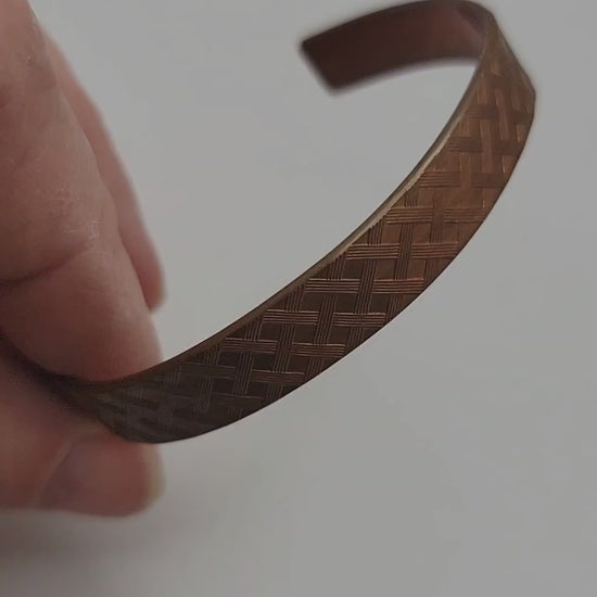 Copper bracelet shown with a hand on a white background