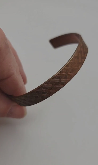Copper bracelet shown with a hand on a white background