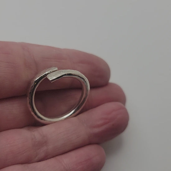 Hand holding a silver ring on a white background