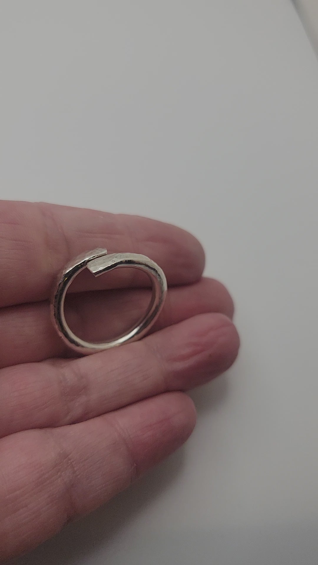 Hand holding a silver ring on a white background
