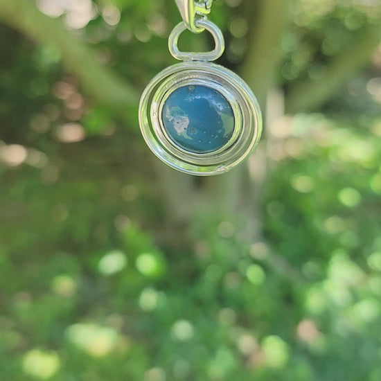 Blue Stone set in sterling silver circular pendant on Sterling Silver chain on nature background
