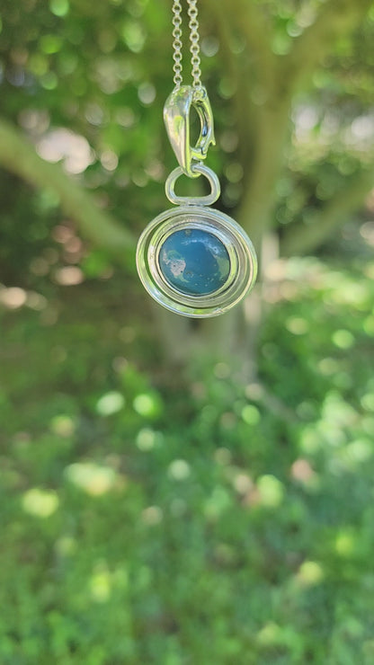 Blue Stone set in sterling silver circular pendant on Sterling Silver chain on nature background