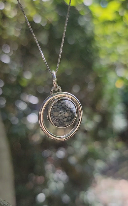 Handmade variscite pendant within an open sterling silver circle with movement in an outdoor environment