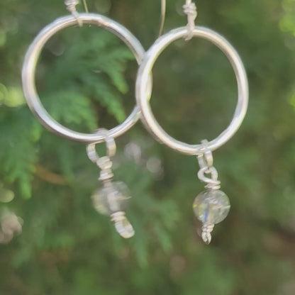 Silver hoop dangle earrings with moonstones on a natural outdoor environment