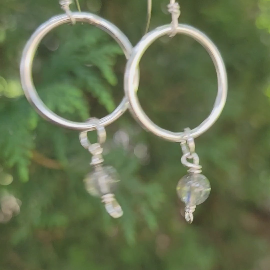Silver hoop dangle earrings with moonstones on a natural outdoor environment