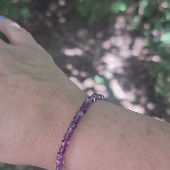 A purple beaded bracelet worn on a wrist in an outdoor environment