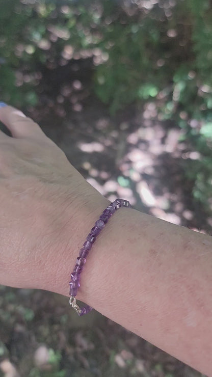 A purple beaded bracelet worn on a wrist in an outdoor environment
