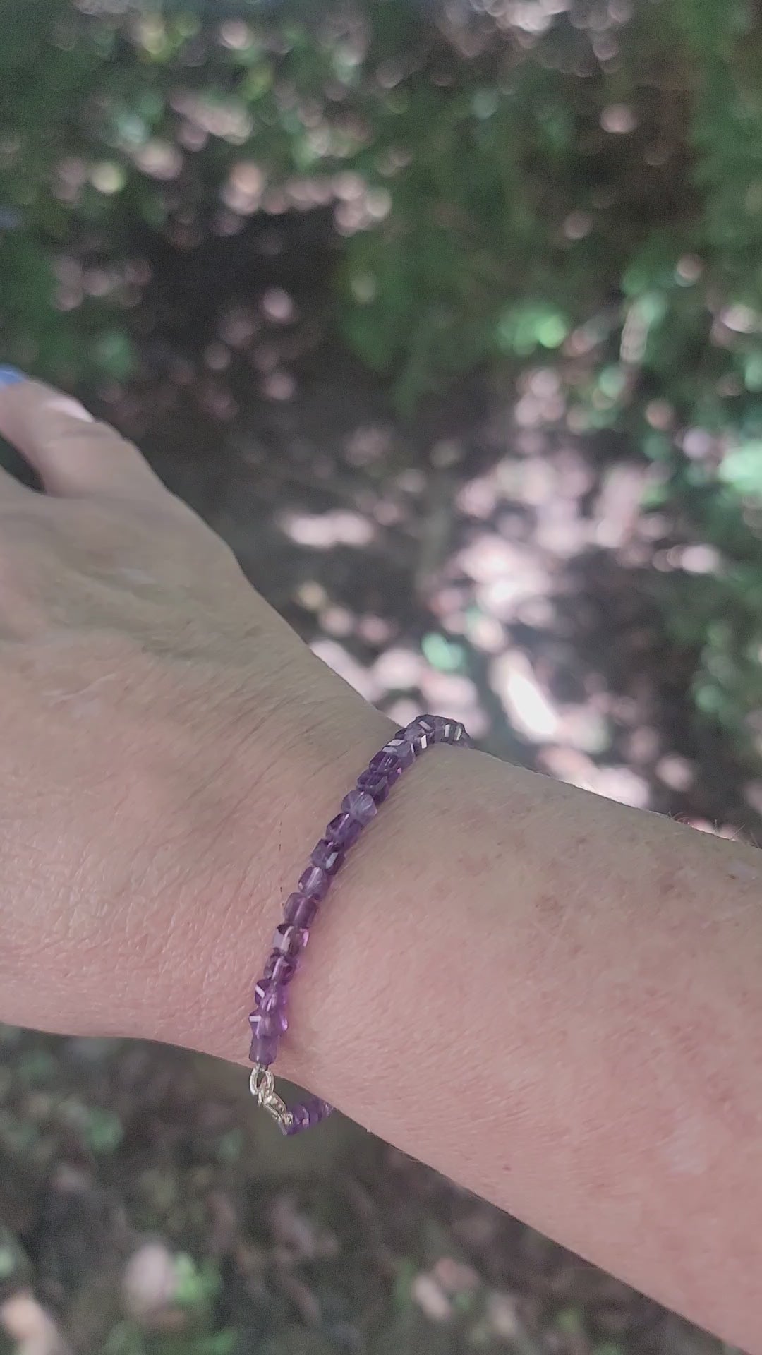 A purple beaded bracelet worn on a wrist in an outdoor environment