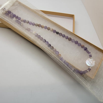 Amethyst and coin pearl necklace in an organza pouch in a cardboard gift box on a white background
