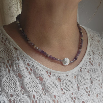 Amethyst and coin pearl necklace being worn on a person next to a window